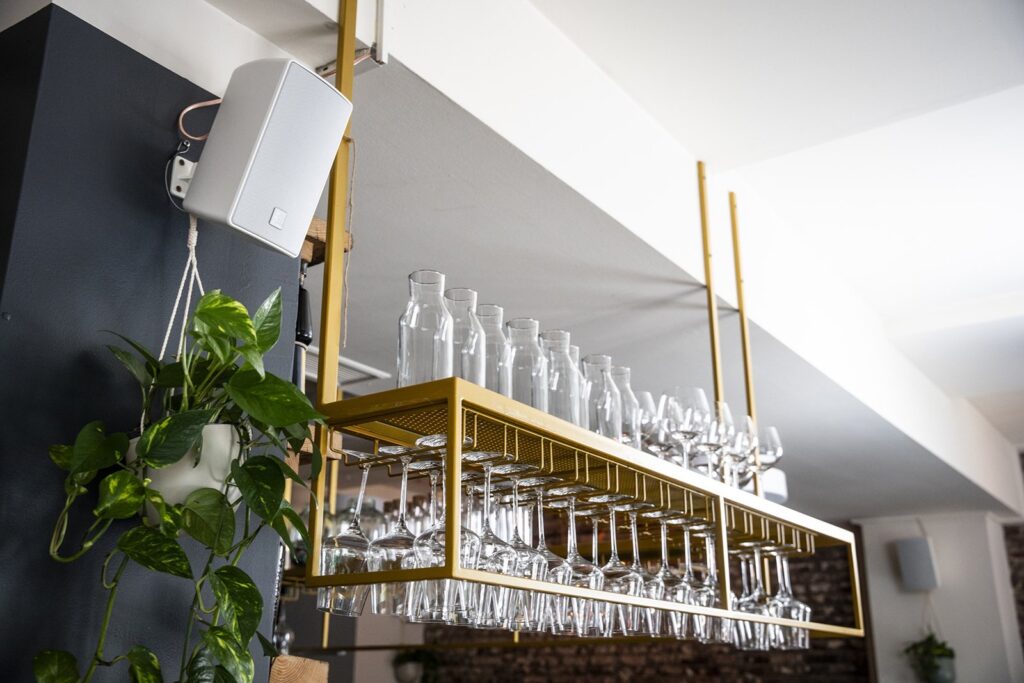 White Optimal Audio Cuboid speaker on a restaurant bar wall